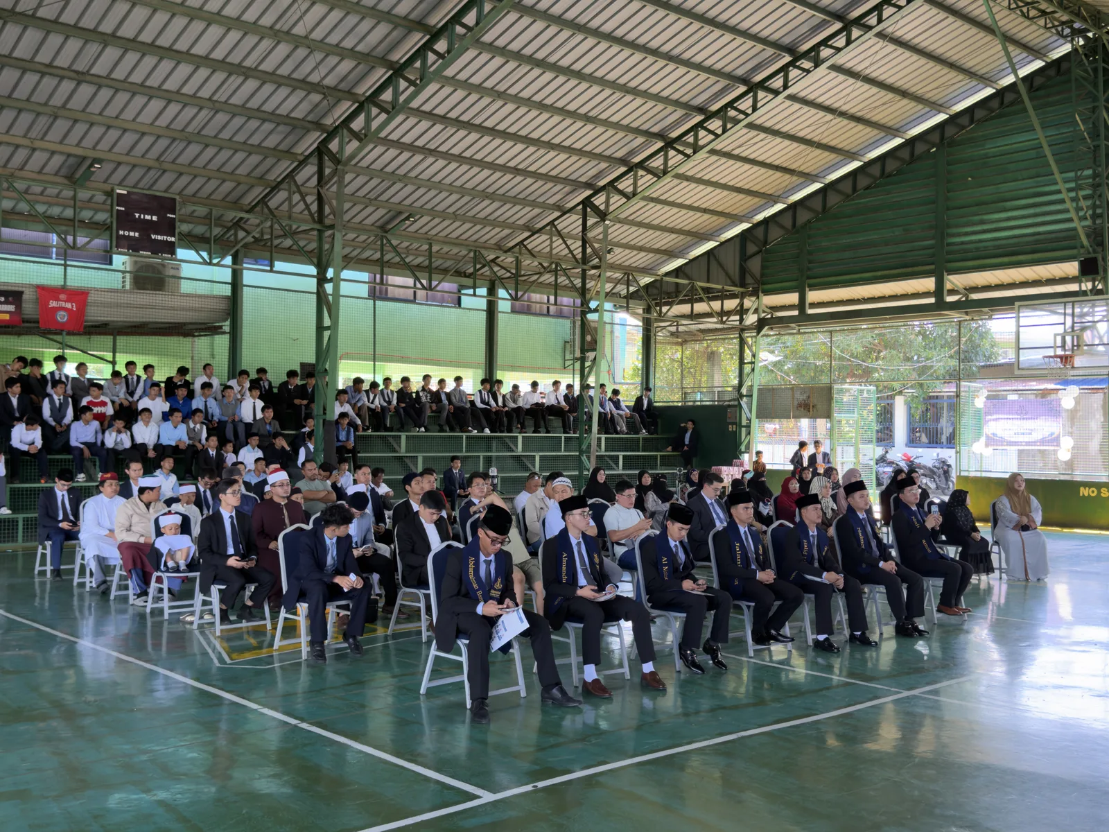 Students seated in rows in a covered hall during the graduation ceremony.
