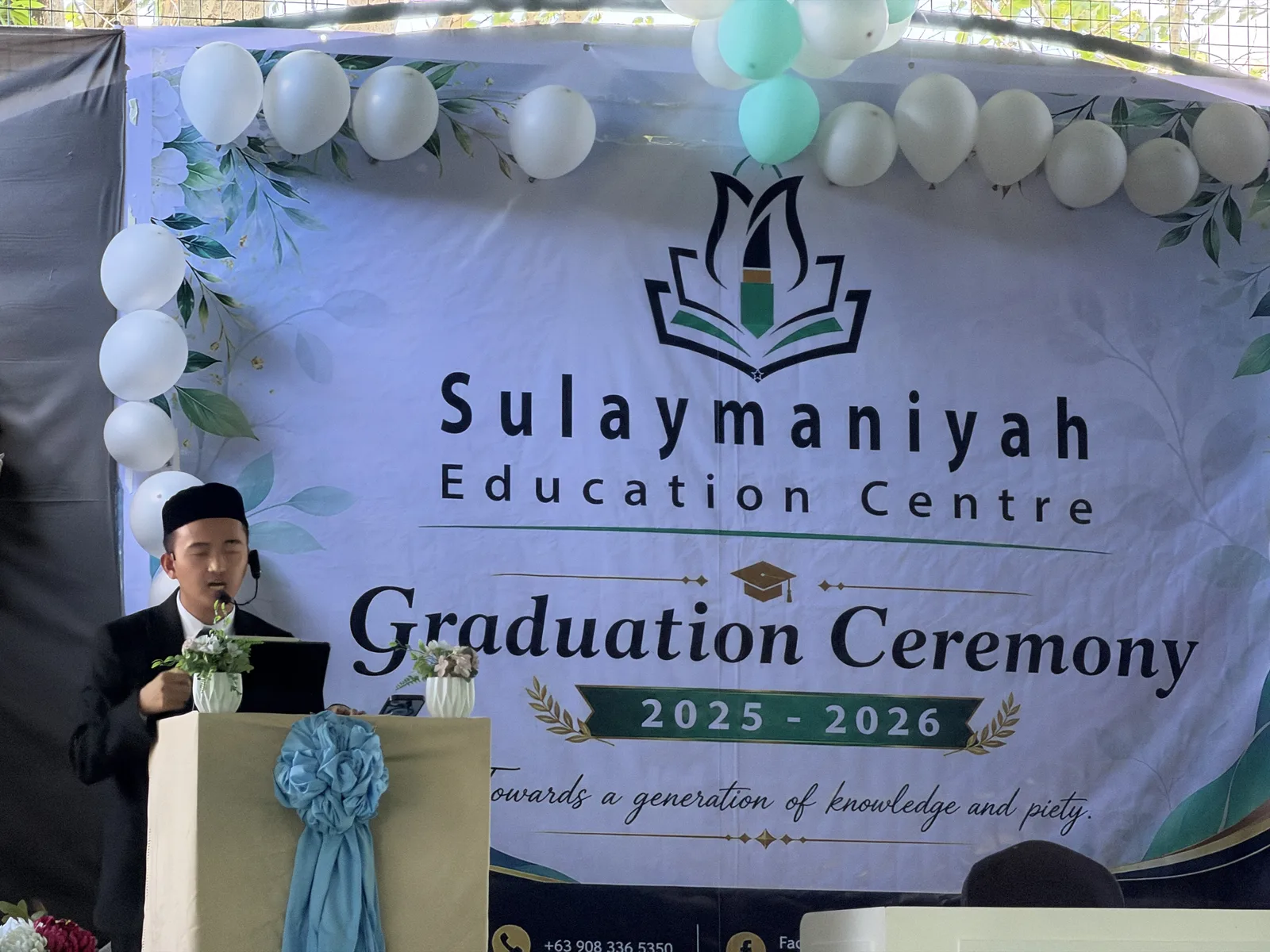 A speaker at the podium beneath a banner reading Sulaymaniyah Education Centre, Graduation Ceremony 2025–2026.