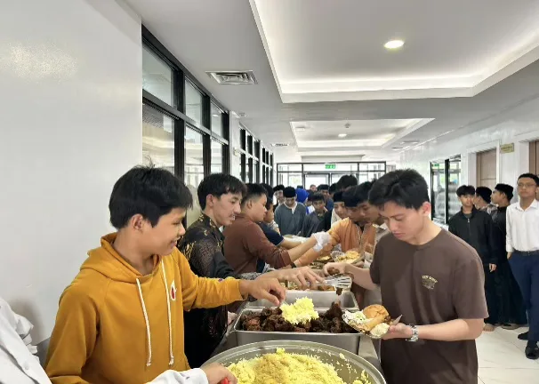 Students serving themselves rice and dishes from large trays.
