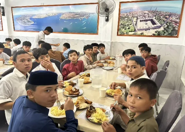 Students eating together at a long table in a dining hall.