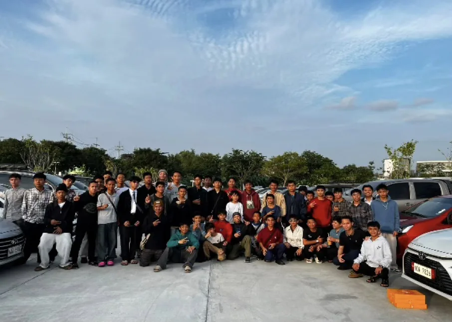 A large group of students posing together outdoors under a cloudy sky.